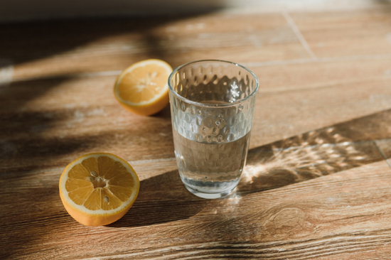 Glass of water surrounded by a cut lemon